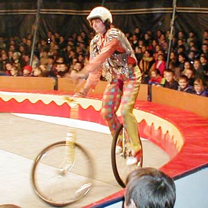 клоун на моноцикле на манеже цирка