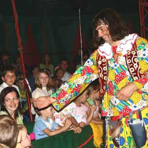 Клоун со зрителями показывает цирковую репризу - Метание ножей на манеже цирка