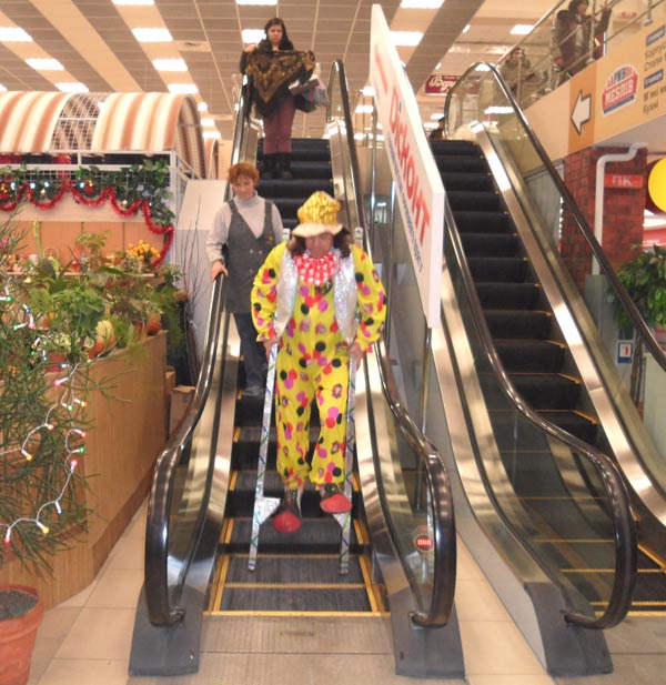 клоун на ходулях на экскалаторе