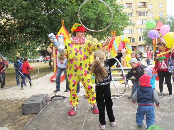 Клоун жонглирует и выступает на сцене детской площадки