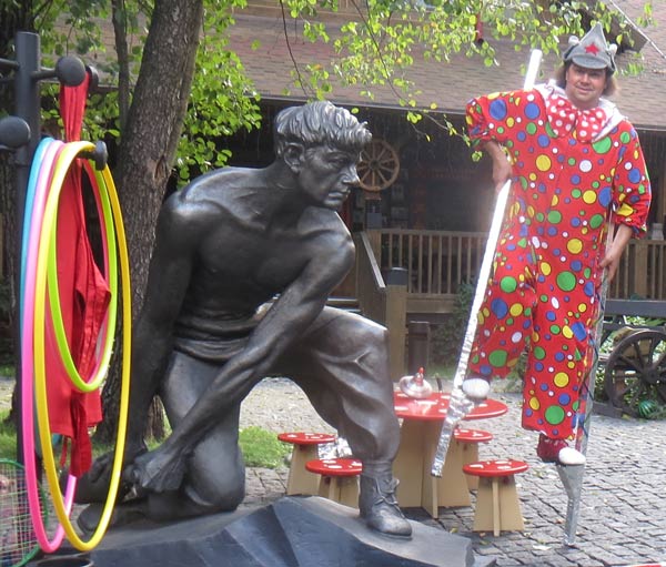клоун на ходулях и памятник партизанам