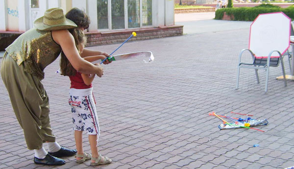 дети учатся стрелять с лука у клоуна
